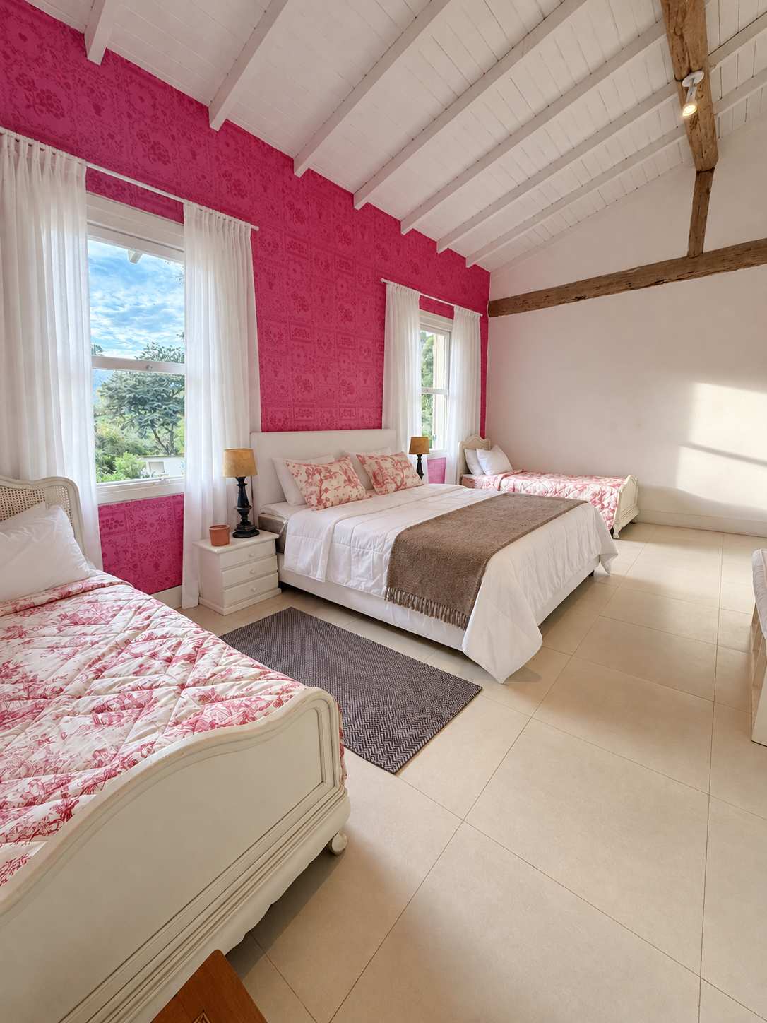 Suíte 05 em outro ângulo: cama de solteiro em primeiro plano, cama king ao centro e a segunda solteiro ao fundo, janela grande com vista para as montanhas